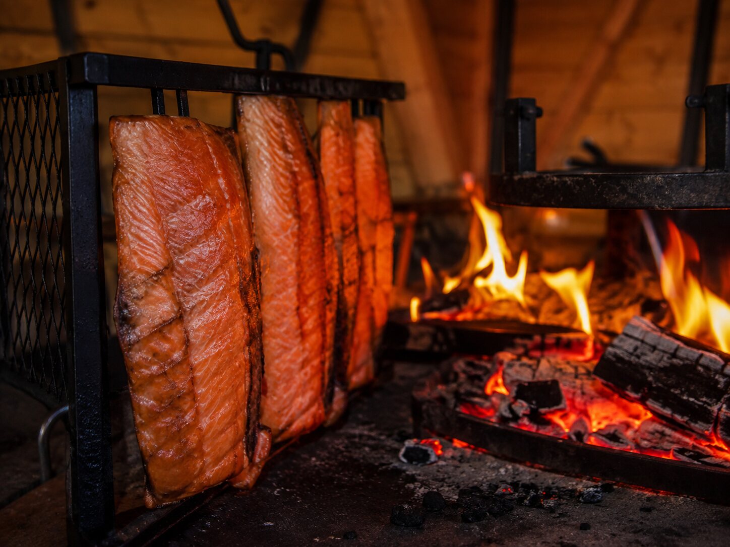 Salmon fillets cooking beside an open wood fire