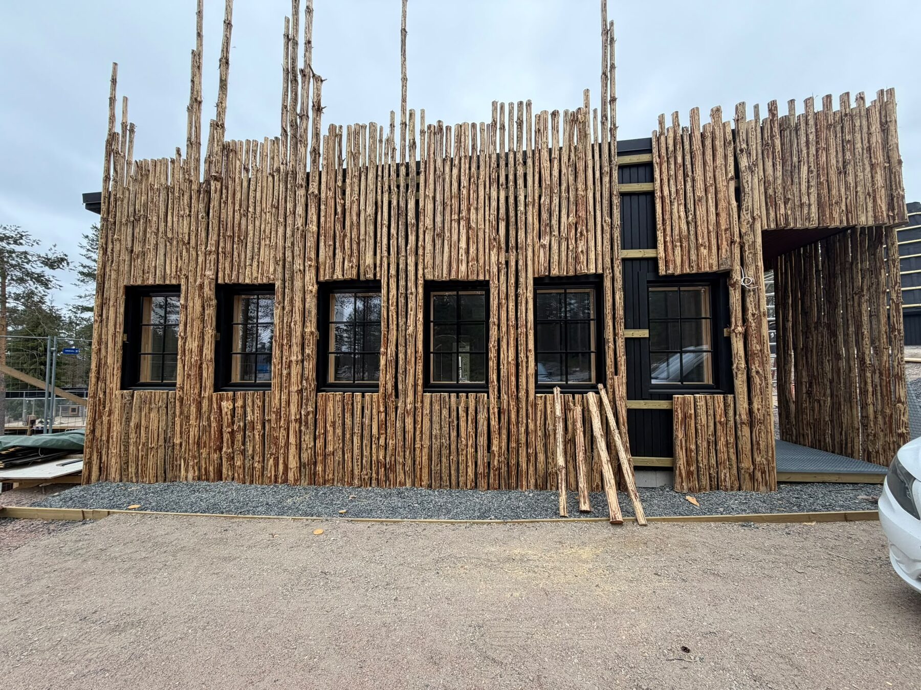 Natural pine trunks and black-framed windows on the new kota facade during construction